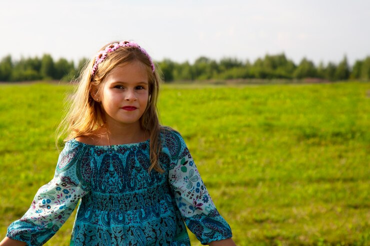 Portret słodkie dziewczynki leżącej na łące. Piękna dziewczyna w wieku 7-9 lat z kręconymi brązowymi włosami.