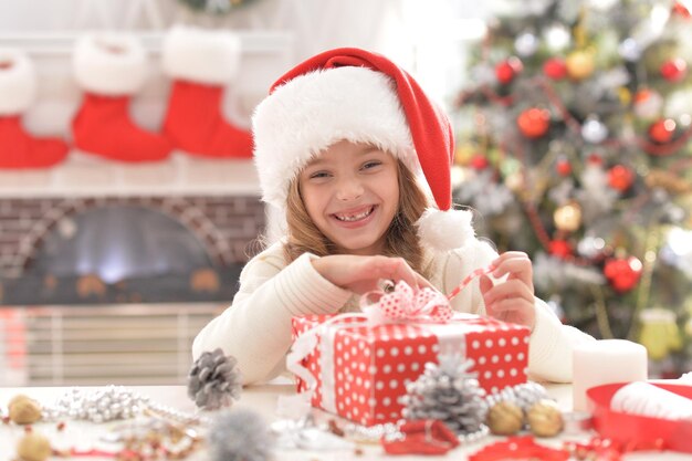 Portret słodkie dziewczynki w Santa hat przygotowuje się do Bożego Narodzenia w domu