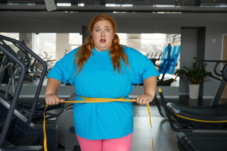 Zdjęcie portret słodkiej kobiety z nadwagą wiąże się z taśmą pomiarową stojącą w siłowni. dieta odchudzająca i trening sportowy dla otyłych kobiet