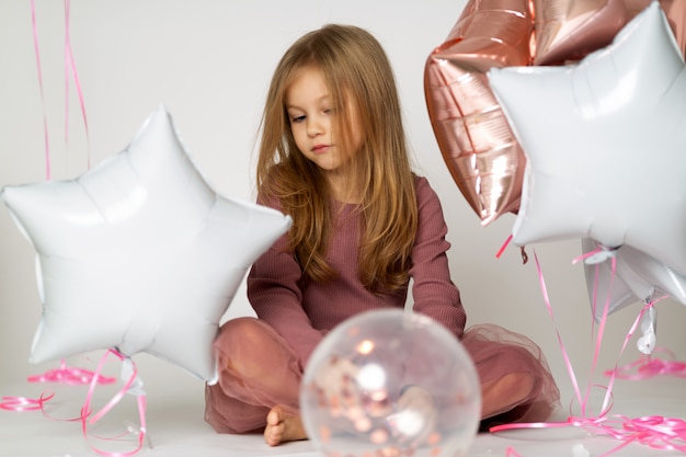 Portret smutna blond mała dziewczynka z kolorowymi balonami