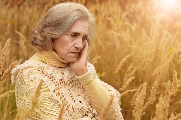 Portret smutnej starszej kobiety w jesiennym parku