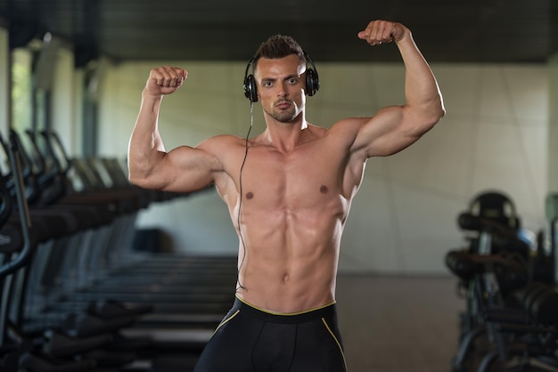 Portret sprawnego fizycznie mężczyzny pozującego na siłowni w nowoczesnym centrum fitness