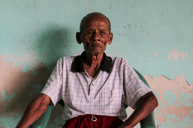 Portret starego indonezyjskiego dziadka siedzącego na krześle