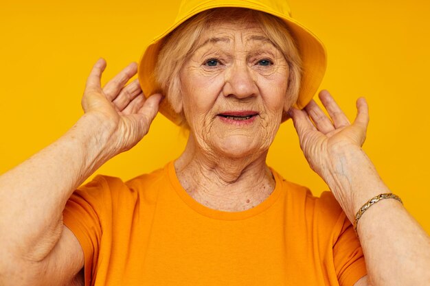 Portret starej, przyjaznej kobiety w kapeluszu z żółtymi koszulkami pozowanie przyciętego widoku
