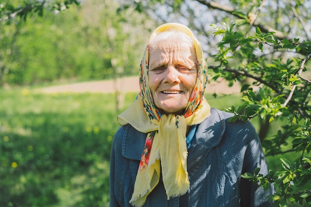 Portret starej szczęśliwej kobiety w żółtej chustce Portret siwej dorosłej babci na tle natury