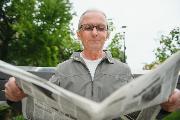 Portret starszego mężczyzny czytającego na ławce w letni dzień