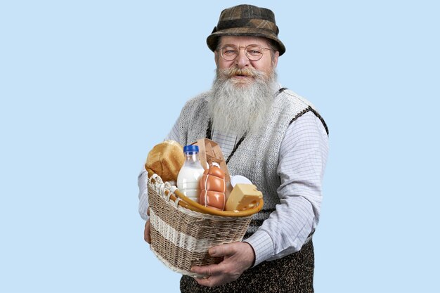 Portret starszego mężczyzny z jedzeniem ze sklepu spożywczego izolowany na pastelowym niebieskim tle