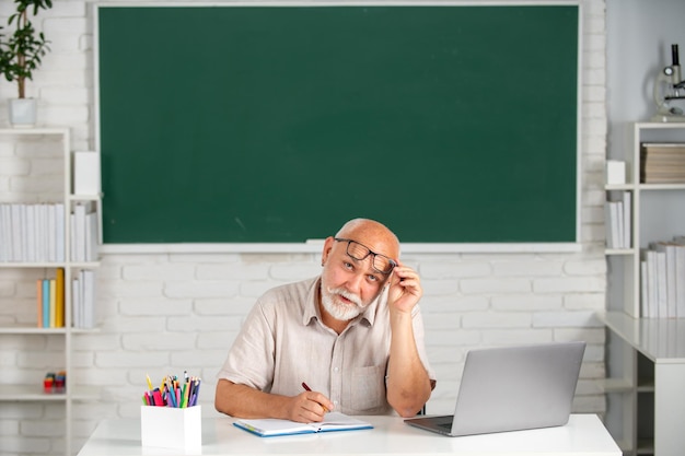 Portret starszego nauczyciela nauczającego linii uczniów liceum z notatnikiem w klasie na czarno...