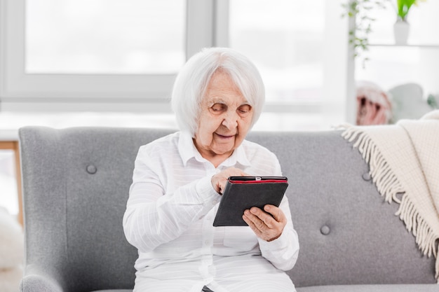 Portret Starszej Gejowskiej Kobiety Siedzącej Na Kanapie W Domu Z Tabletem I Patrzącej Na Ekran