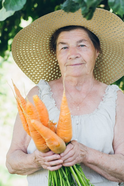 Portret starszej kobiety w kapeluszu, trzymając marchewkę