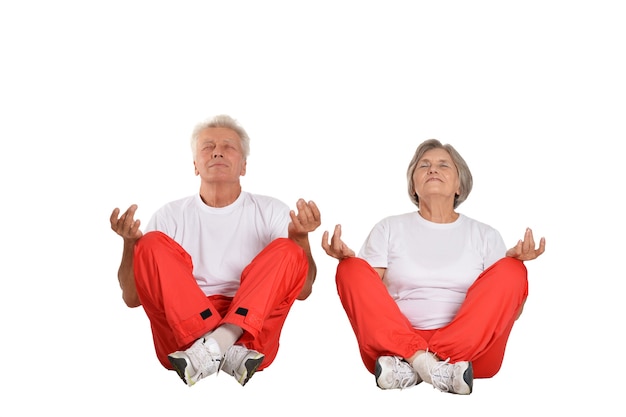 Zdjęcie portret starszej pary medytującej na podłodze na białym tle