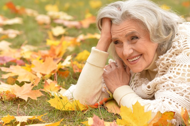 Portret starszej pięknej kobiety leżącej na liściach