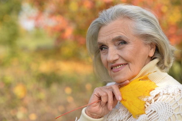 Portret starszej pięknej kobiety trzymającej jesienny liść