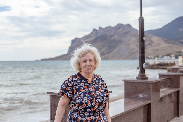 Portret starszej siwowłosej kobiety na nabrzeżu morza. Rekreacja i rozrywka na emeryturze.