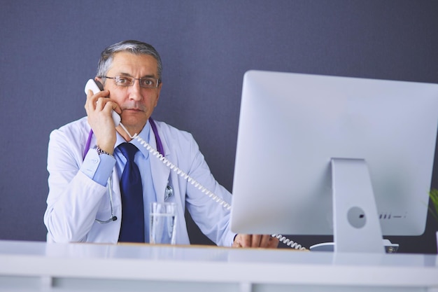 Portret starszy lekarz siedzi w biurze medycznym