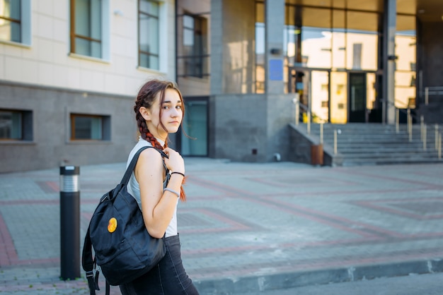 Portret student uniwersytetu z plecakiem podczas gdy iść do szkoły wyższa od ulicy