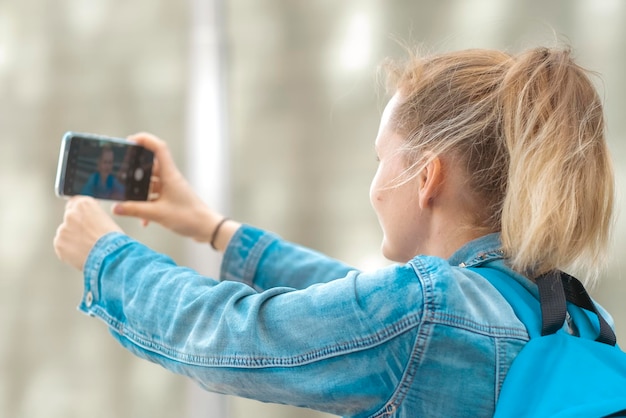 portret studentki lub podróżniczki z plecakiem biorącej telefon do selfie