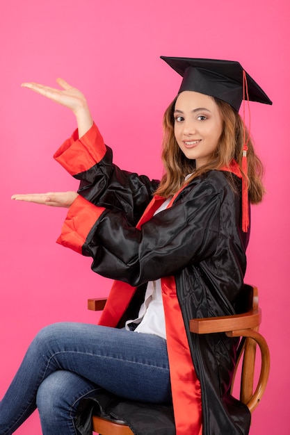 Portret Studentki Na Sobie Suknię Ukończenia Szkoły I Trzymając Ręce W Górę.