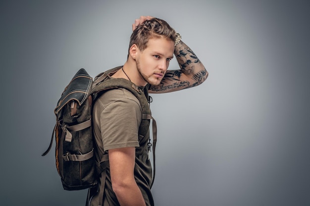 Portret Studio Backpackers miejskiego stylu z tatuażem na ramionach w tle szarym winiety.