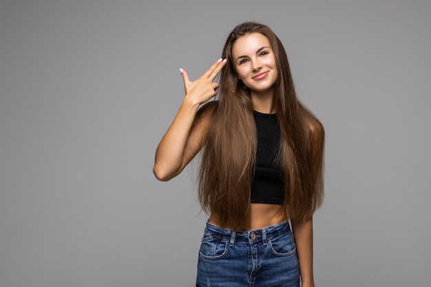 Portret studio strzał głową na szarym tle, ponura kobieta w okularach patrząc na kamery kładzie palce pistolet skierowany na głowę zabijając się gest, symbol wyczerpania duże problemy koncepcja nieszczęśliwej kobiety