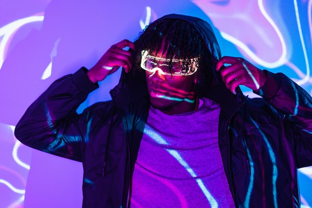 Portret studyjny z fioletowymi i niebieskimi neonami cyber-mężczyzny w futurystycznych inteligentnych goglach