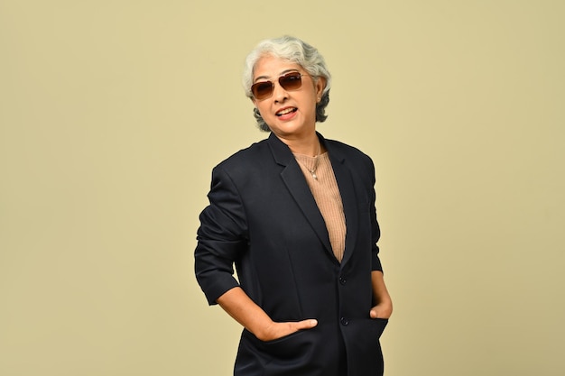 Portret stylowej bizneswoman z lat 50. w okularach przeciwsłonecznych stojącej na białym tle beżowym