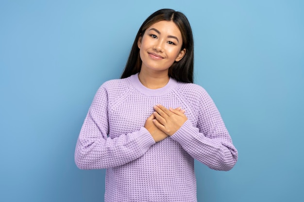 Portret szczerej, uczciwej nastolatki w bluzie z kapturem, trzymającej rękę na klatce piersiowej