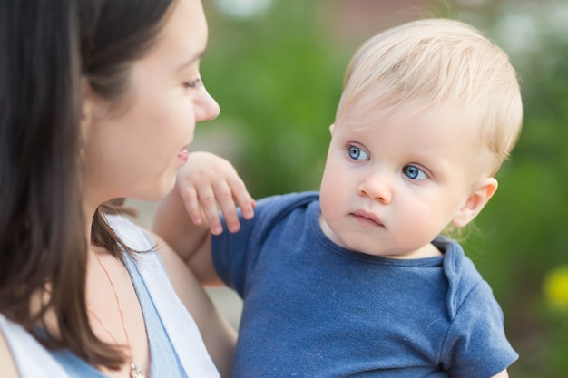 Portret szczęśliwa kochająca matka i jej babyboy na zewnątrz. Mama trzymająca dziecko w parku