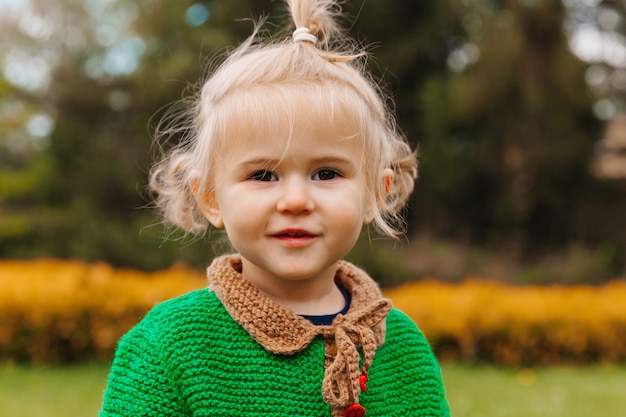 Portret szczęśliwa mała dziewczynka w jesienne ubrania. dziecko śmieje się na tle natury.