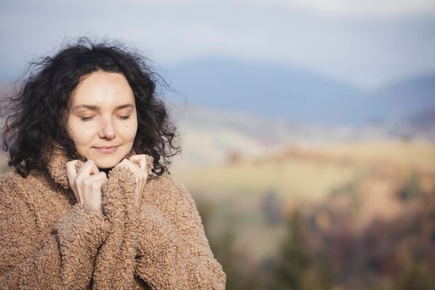 Zdjęcie portret szczęśliwa piękna dziewczyna z zamkniętymi oczami na tle gór. emocje i nastrój