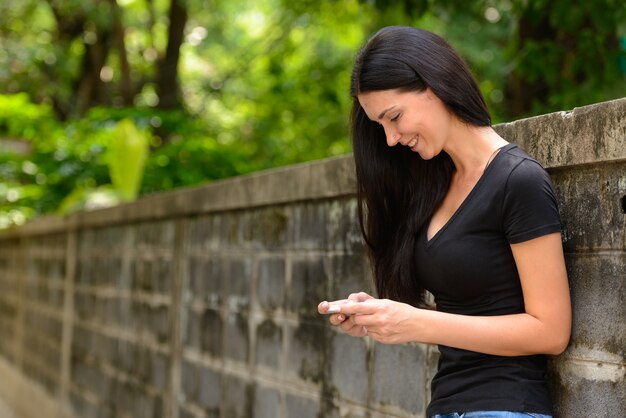 Portret szczęśliwa piękna kobieta za pomocą telefonu na zewnątrz