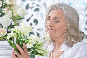 Zdjęcie portret szczęśliwa starsza kobieta pozuje z kwiatami