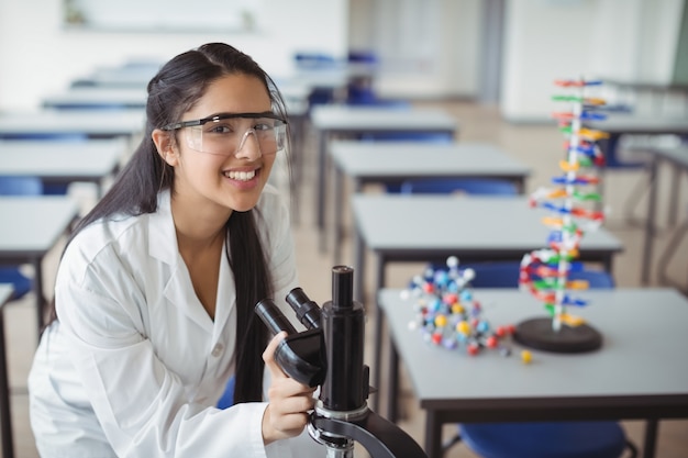 Portret szczęśliwa uczennica trzyma mikroskop w laboratorium