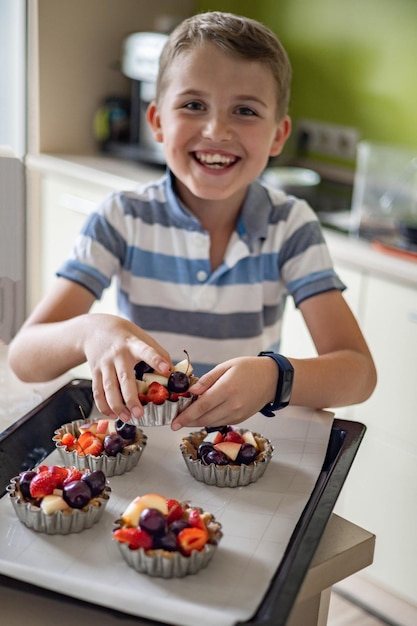Portret Szczęśliwego Chłopca Pozującego Z Blachą Do Pieczenia Pełną Letniego Deseru Gotowego Do Gotowania W Domu