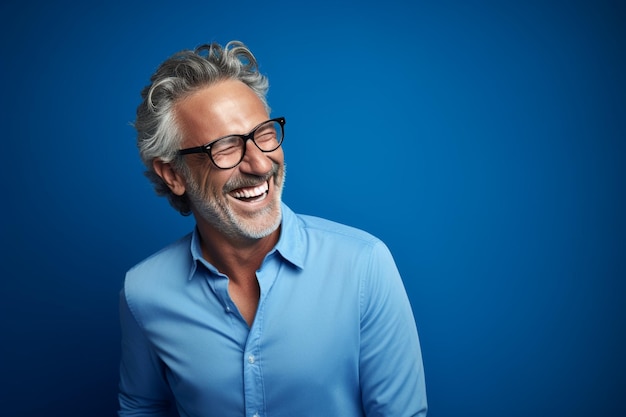 Portret szczęśliwego dojrzałego mężczyzny w okularach śmiejącego się na niebieskim tle