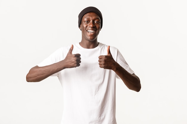 Portret Szczęśliwego I Zadowolonego, Uśmiechniętego Afroamerykańskiego Młodzieńca W Czapce, Pokazującego Aprobatę, Jak Coś Dobrego