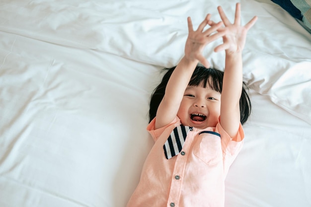 Portret szczęśliwego małego chłopca wesołego w białej sypialni Mały chłopiec jest szczęściem na łóżkuSzczęśliwa koncepcja życia rodzinnego