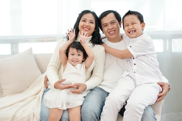 Portret szczęśliwego małżeństwa z dwójką dzieci siedzących na kanapie w domu
