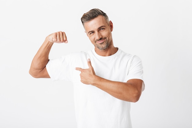 Portret Szczęśliwego Mężczyzny W Wieku 30 Lat Z Włosiem W Swobodnym T-shircie Pokazującym Jego Bicepsy Na Białym Tle