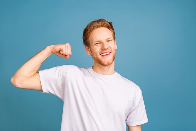 portret szczęśliwego młodego mężczyzny ubranego w t-shirt pokazujący biceps