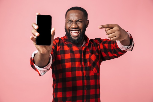 Portret szczęśliwego przypadkowego afrykańskiego mężczyzny stojącego na białym tle, pokazującego pusty ekran telefonu komórkowego