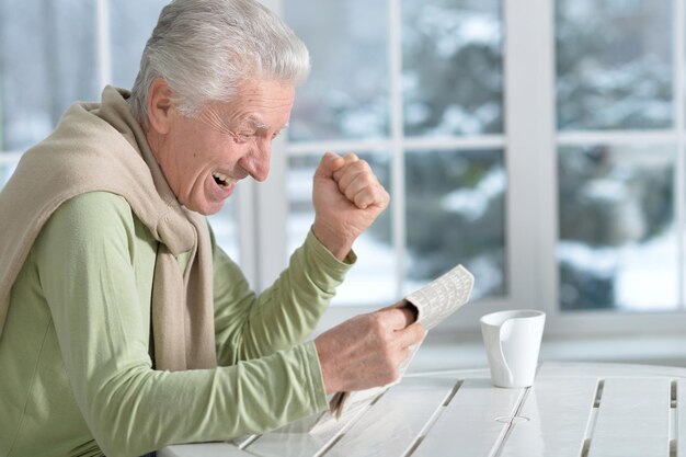 Portret szczęśliwego starszego mężczyzny czytającego gazetę
