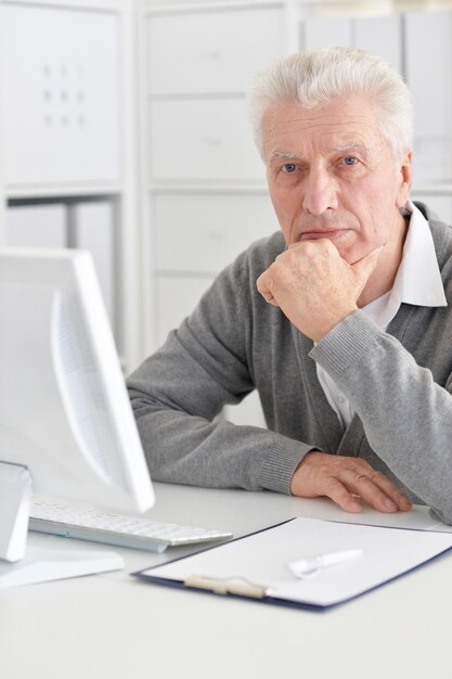 Portret szczęśliwego starszego mężczyzny pracującego z komputerem