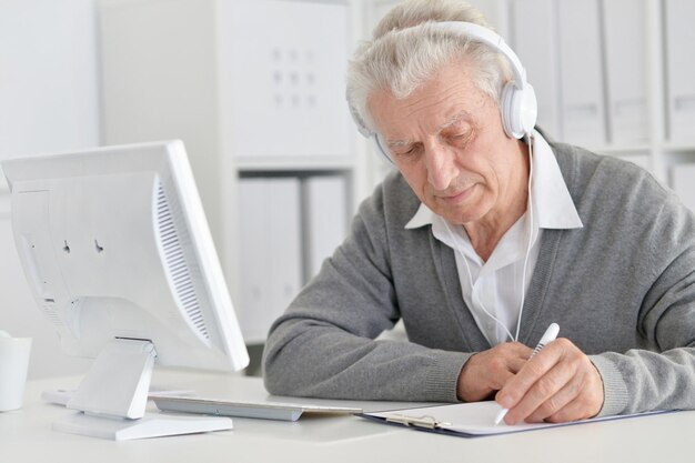 Portret szczęśliwego starszego mężczyzny pracującego z komputerem