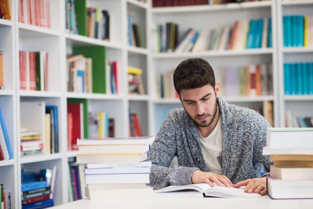 Portret szczęśliwego ucznia czytającego książkę w szkolnej bibliotece Ucz się lekcji na egzamin Ciężko pracujący i wytrwały