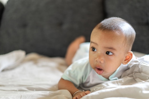 Portret szczęśliwego uśmiechu azjatyckiego chłopca relaksującego patrzącego na kamerę Śliczny azjatycki noworodek na łóżku w domu