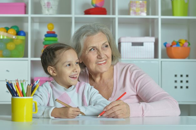 Portret szczęśliwej babci z wnuczką rysującą razem