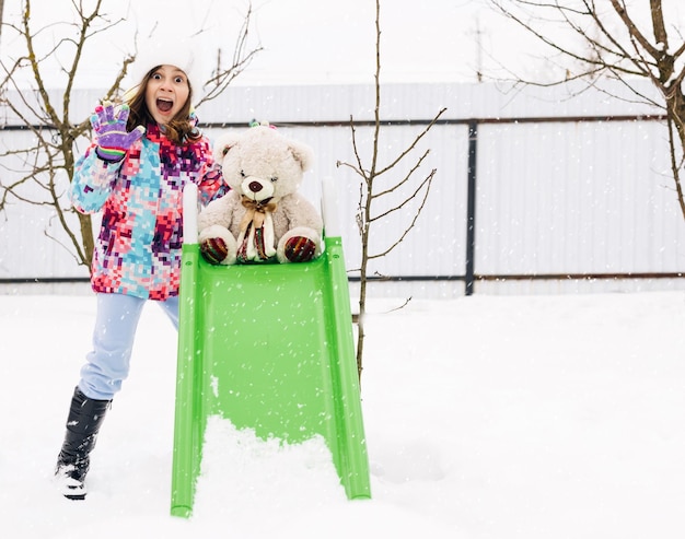 Portret szczęśliwej dziewczynki bawiącej się misiem na zimowym spacerze w przyrodzie na świeżym powietrzu na zimę