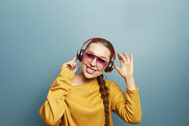 Portret szczęśliwej dziewczyny słuchającej muzyki przez bezprzewodowe słuchawki ze smartfona