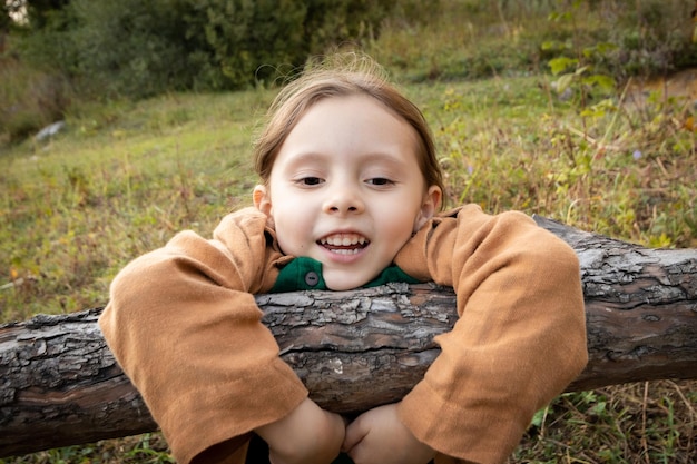 Portret szczęśliwej dziewczyny w wieku 6 lat wiszącej na gałęzi drzewa na wolności